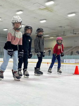 Four children learning to ice skate.